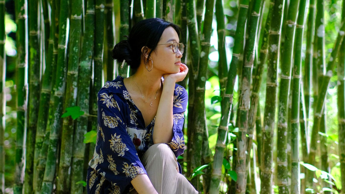 Asian American woman sitting in front of bamboo