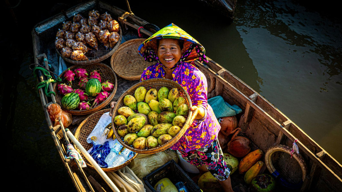 Southeast Asian woman holding mangoes in a boat