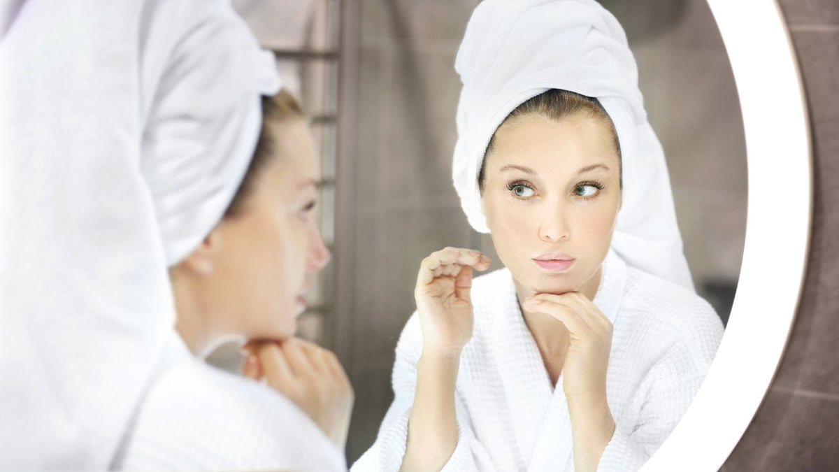 woman looking at skin in a mirror