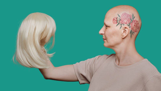 bald woman holding a wig in her hands