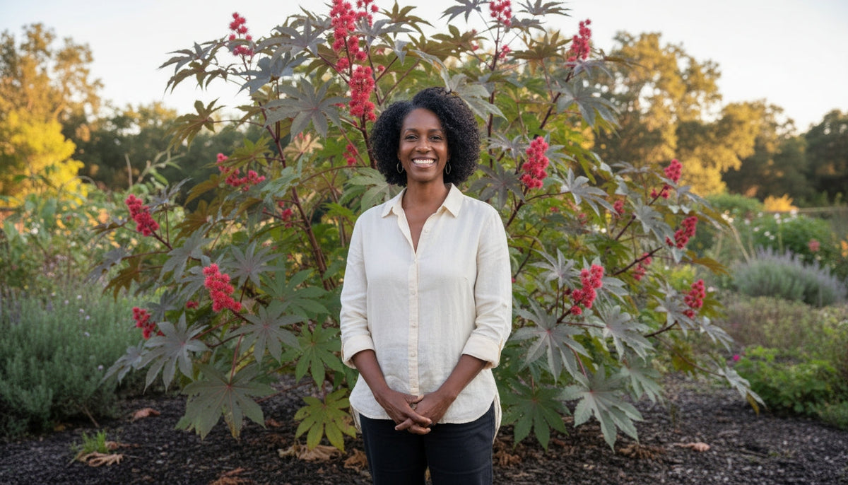 An African woman is standing in front of a castor bush smiling