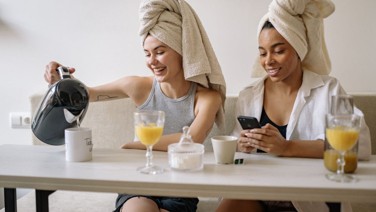 Two woman with hair in towels having morning tea and orange juice