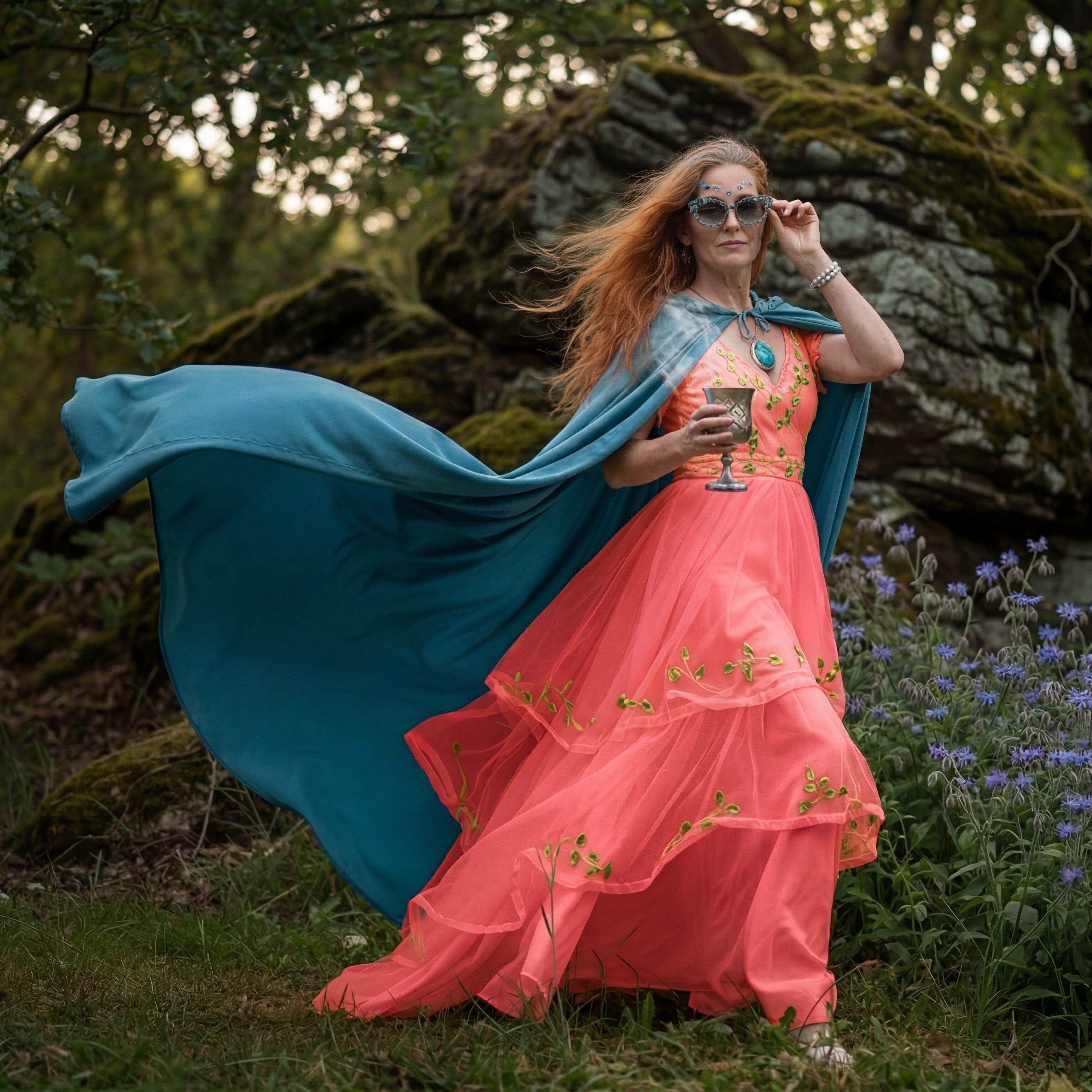 Woman with sensitive skin posing in a coral druid dress and teal cape