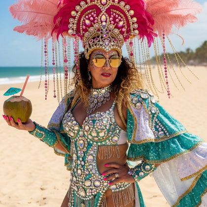 Latina samba dancer in elaborate costume with pink feathers and beads on a beach